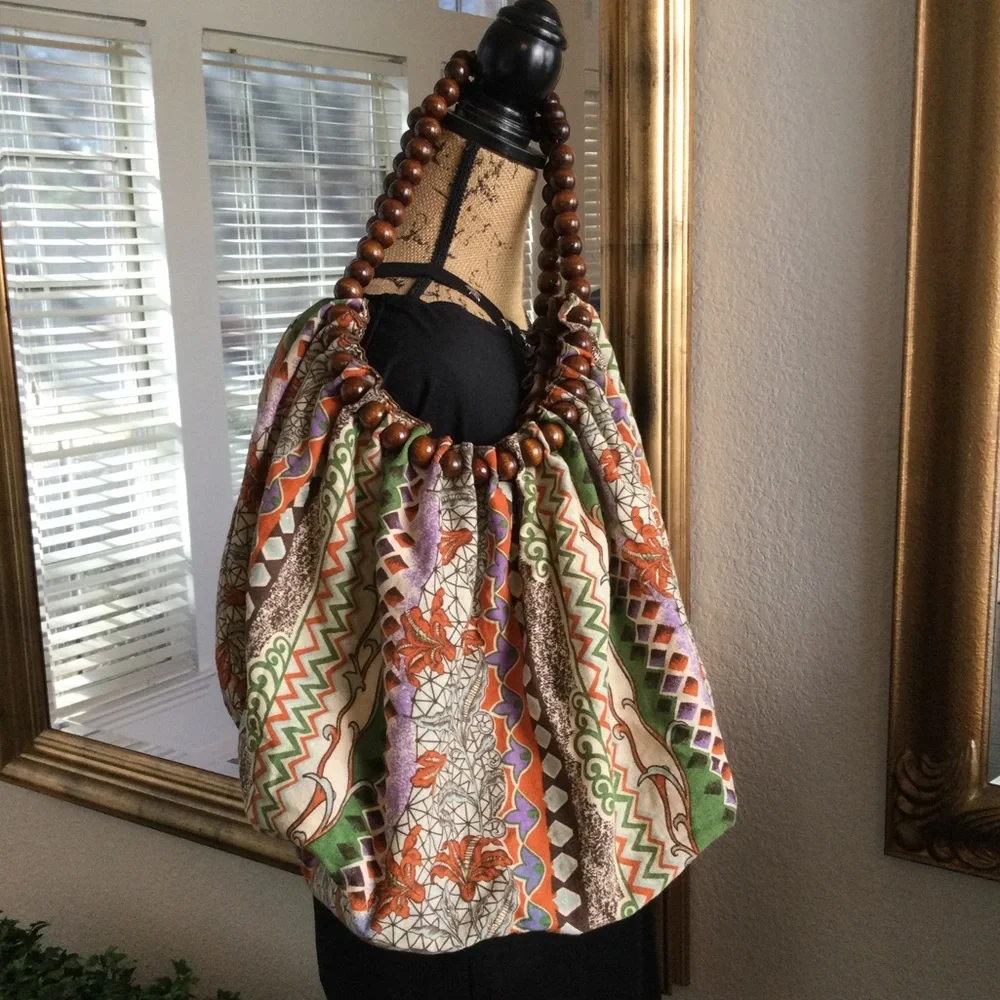 Reversible hobo tote with brown wood balls straps. Has a tie strap closu…